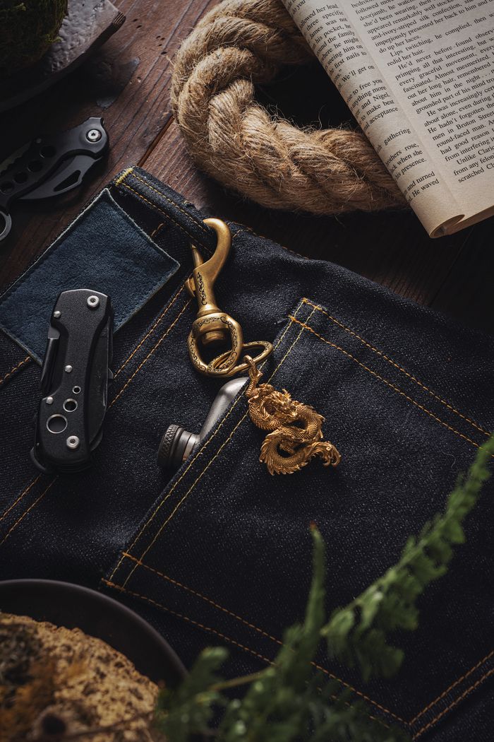 Golden dragon pendant and accessories on denim, showcasing elegance and craftsmanship.