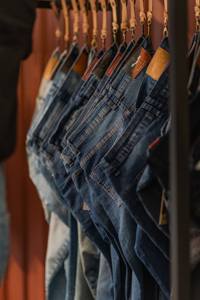 Close-up of blue denim jeans on hangers in a fashion store.